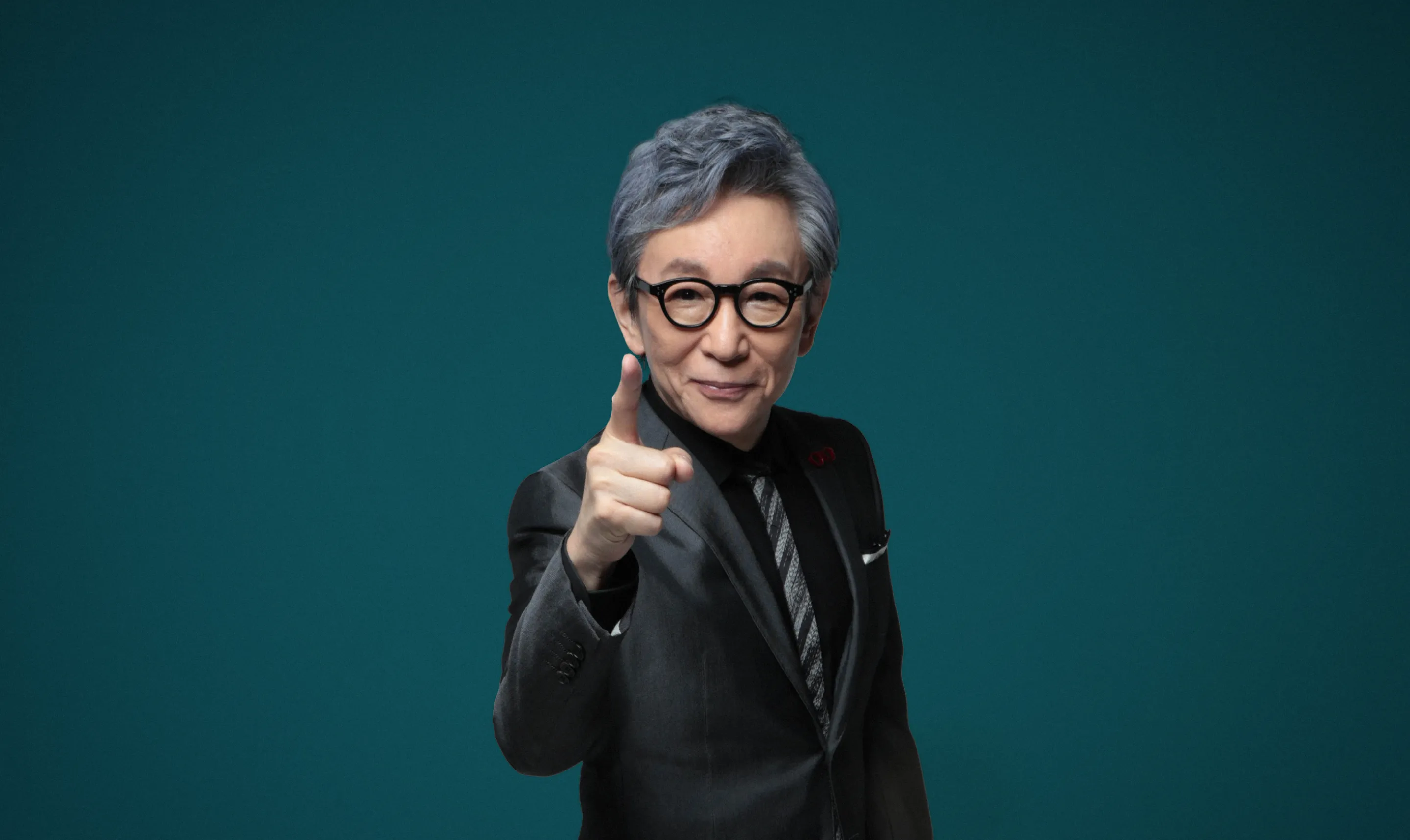 古舘伊知郎さんが正面を向いて指を指している写真